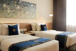 a hotel room with two beds with blue pillows at Antero Hotel Jababeka in Cikarang