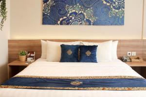 a bedroom with a bed with blue and white pillows at Antero Hotel Jababeka in Cikarang