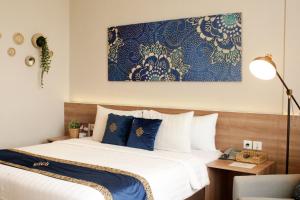 a bedroom with a bed with blue and white sheets at Antero Hotel Jababeka in Cikarang