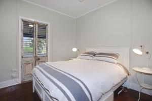 a white bedroom with a large bed and a window at Sunroom Cottage in Tea Gardens