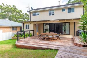 a wooden deck in front of a house with a table and chairs at Central Coast - Luxurious Beach House 400m to Beach in Bateau Bay