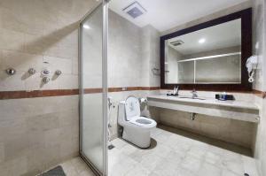 a bathroom with a shower and a toilet and a sink at ASTON Jayapura Hotel and Convention Center in Jayapura