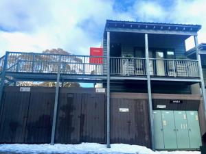 a house with a balcony and a fence with snow at THE HANGAR, alpine-getaways in Dinner Plain