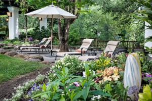 um jardim com cadeiras e um guarda-sol e flores em Candlelight Inn Napa Valley em Napa