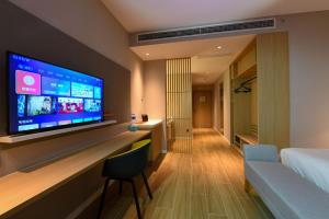 Holiday Inn Express Tianjin Binhai, an IHG Hotel في Binhai: غرفة في الفندق مع تلفزيون بشاشة مسطحة كبيرة على الحائط