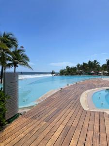 a swimming pool on the beach with a wooden deck at Bay View Grand Marina Ixtapa condo en pie de playa in Ixtapa