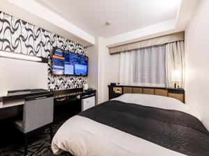 a hotel room with a bed and a desk and a tv at APA Hotel Ueno Ekiminami in Tokyo