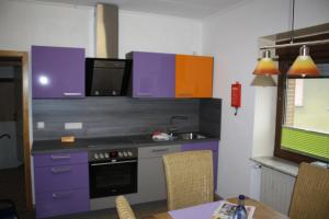 ノインキルヒェンにあるHoliday home Paulaのキッチン(紫色のキャビネット、シンク、テーブル付)