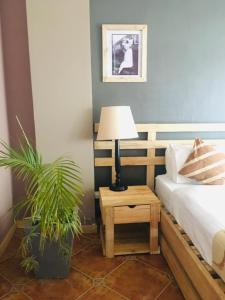 um quarto com uma cama e uma mesa com um candeeiro em The Greenville Home em Mbarara