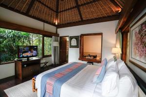 a bedroom with a large bed and a television at Umah Lawas Villa Ubud in Ubud