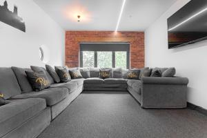 sala de estar con sofá gris y pared de ladrillo en The Headingley House Leeds - Hot Tub - Sleeps Up To 12 - EV Charging, en Leeds