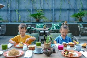 zwei Kinder sitzen an einem Tisch und essen Essen in der Unterkunft Holiday Inn Bali Sanur, an IHG Hotel in Sanur