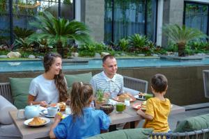 a family sitting at a table eating food at Holiday Inn Bali Sanur, an IHG Hotel in Sanur