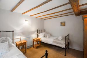 two twin beds in a room with two tables at Meadow Brook Cottage in Blockley