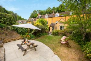 a patio with a table and an umbrella and two chairs at Meadow Brook Cottage in Blockley