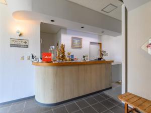 a restaurant with a counter in a room with a bench at Tabist Station Hotel Isobe Ise-Shima in Shima