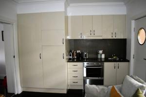 una cucina con armadietti bianchi e piano cottura di The George @ The “G” a Melbourne