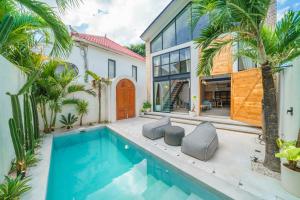 a pool in the backyard of a house with palm trees at Villa Upeksha - Huge 1-bedroom Villa with pool in Pererenan in Munggu