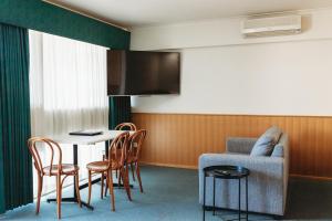 a room with a table and chairs and a tv at Echuca Nirebo Motel in Echuca