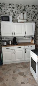 a kitchen with white cabinets and a microwave at Ferienwohnung Sommerbrise in Gelbensande