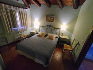 a bedroom with a bed with two lamps and two chairs at Hotel Albarrán in Albarracín