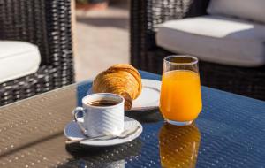 a table with a cup of orange juice and a plate of bread at Muses villa in Pastida