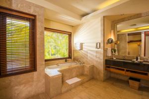 bagno con vasca, lavandino e specchio di Shanti Maurice Resort & Spa a Chemin Grenier