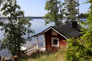 una pequeña casa roja a orillas de un lago en Ylatupa, en Kesälahti