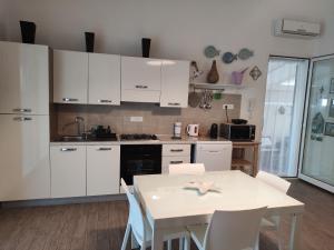 a kitchen with white cabinets and a table with chairs at Villa Punta Piccola sul mare in Porto Empedocle