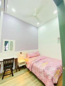 - une chambre avec un lit rose et un bureau dans l'établissement Homestay Myya, à Beris Tok Saboh