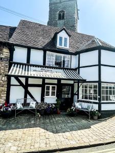 a black and white building with two benches in front of it at Humbug Cottage in Much Wenlock