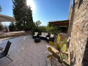 patio z kanapami i krzesłami obok kamiennej ściany w obiekcie Ninetta House w mieście Selva di Fasano