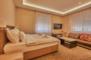een slaapkamer met een bed en een bank bij Hotel Cataleya in Šabac