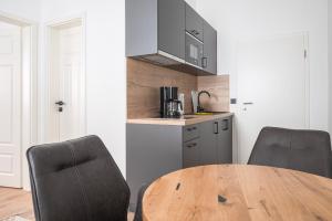 uma cozinha com uma mesa de madeira e 2 cadeiras em JOHOUSE Apartment 3 em Warnemünde