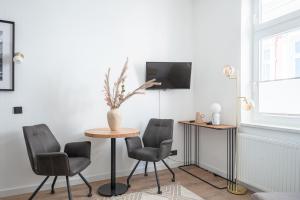 Cette chambre dispose d'une table, de deux chaises et d'une télévision. dans l'établissement JOHOUSE Apartment 08, à Warnemünde