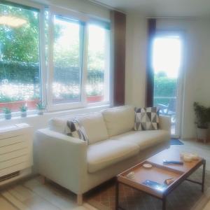 ein Wohnzimmer mit einem weißen Sofa und Fenstern in der Unterkunft Saint Nicholas Varna Lovely 2 bedroom apartment with sunny garden in Warna