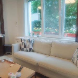 - un canapé blanc dans le salon avec deux fenêtres dans l'établissement Saint Nicholas Varna Lovely 2 bedroom apartment with sunny garden, à Varna