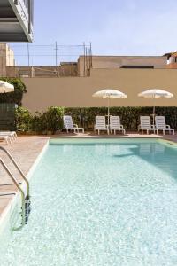una piscina con sedie e ombrelloni di Hotel Villa Margherita a Ladispoli