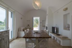 una cucina e una sala da pranzo con tavolo in legno di Villa degli Ulivi con piscina by Wonderful Italy a Ostuni