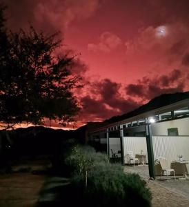 a red sky over a house with a table and chairs at Asher Stable Stay in De Rust