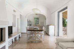 una cucina e un soggiorno con tavolo e TV di Villa degli Ulivi con piscina by Wonderful Italy a Ostuni