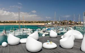 eine Gruppe weißer Stühle auf einem Dock mit Booten in der Unterkunft Barceló Fuerteventura Royal Level in Caleta de Fuste