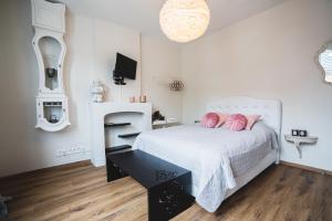 Un dormitorio con una cama blanca con almohadas rosas. en La Villa Delsa, en Namur