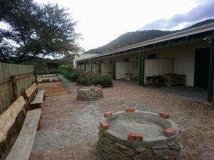 a patio with a fire pit and benches in front of a building at Asher Stable Stay in De Rust