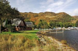 a house on the shore of a body of water at Ardlui Lochside Lodges in Ardlui