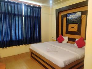 a bedroom with a bed with red pillows and a window at Hotel Amandeep in Dharamshala