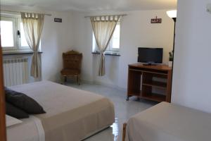 1 dormitorio con 2 camas, TV y escritorio en B&B Privileged, en Pollena Trocchia