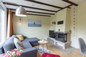 a living room with a blue couch and a fireplace at Duinland 135 Sint Maartenszee in Sint Maartensvlotbrug