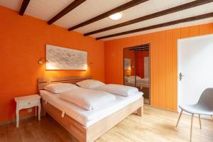 Sint Maartensvlotbrug的住宿－Duinland 135 Sint Maartenszee，一间卧室拥有橙色的墙壁,配有一张床和椅子