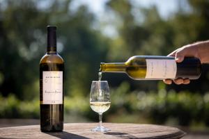 a person pouring a bottle of wine into a glass at Bastide de Fave in Brue-Auriac